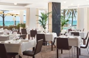 a restaurant with white tables and chairs and the ocean at Pure Salt Garonda - Adults Only in Playa de Palma