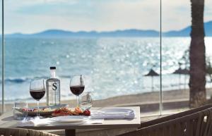 a table with two glasses of wine and a plate of food at Pure Salt Garonda - Adults Only in Playa de Palma