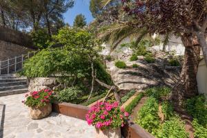 een tuin met roze bloemen en een palmboom bij Pure Salt Port de Sóller in Port de Soller