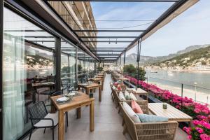 ein Restaurant mit Tischen und Stühlen und Blick aufs Wasser in der Unterkunft Pure Salt Port de Sóller in Port de Sóller
