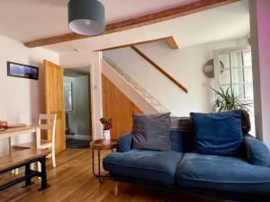 a living room with a blue couch and a staircase at Quiet & Cosy 2-Bedroom Cottage in Coltishall in Coltishall