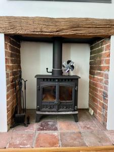 chimenea de ladrillo con estufa en la habitación en Quiet & Cosy 2-Bedroom Cottage in Coltishall en Coltishall
