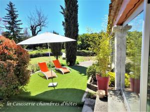 un patio con 2 sillas y una sombrilla en La Causserie, 2 Chambres d'Hôtes, 2 à 4 invités, pour vous seuls en Gramat