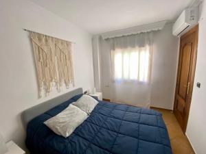 a bedroom with a blue bed and a window at Ático Lanjarón in Lanjarón