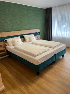 Art Hotel Eifel في هايمباخ: سريرين في غرفة نوم مع جدار أخضر