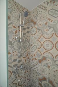 a shower in a bathroom with a mosaic wall at To Patriko Mas Guesthouse-2 in Palaios Panteleimonas