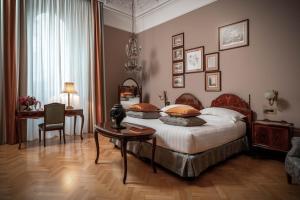 a bedroom with a bed with a table and a desk at Grand Hotel et de Milan - The Leading Hotels of the World in Milan