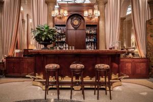 a bar with two bar stools and a clock at Grand Hotel et de Milan - The Leading Hotels of the World in Milan
