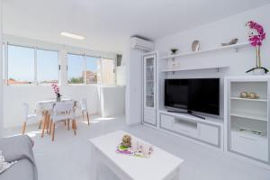 a white living room with a tv and a table at La Mata Londres 2 in La Mata