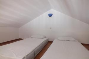 two beds in a small white room with a blue bulb at Anastasia Apartments (Chorio) in Symi