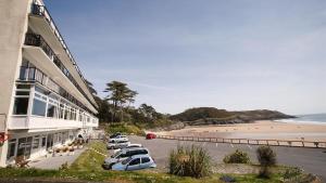 a row of cars parked in a parking lot next to a beach at Redcliffe Apartments A in Bishopston