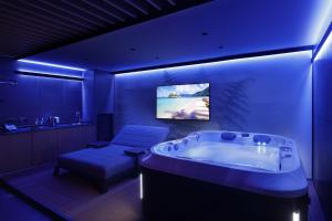 - une grande salle de bains avec une grande baignoire et un canapé dans l'établissement VERSOVERDE HOTEL Alzaia Naviglio Grande, à Milan