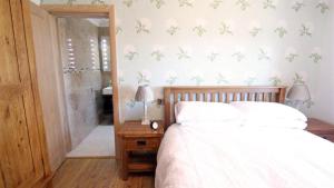 1 dormitorio con 1 cama con sábanas blancas y mariposas en la pared en Coastal View, en Oxwich