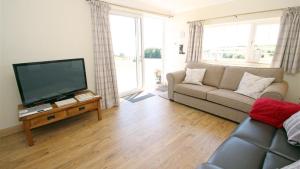 uma sala de estar com um sofá e uma televisão de ecrã plano em Coastal View em Oxwich