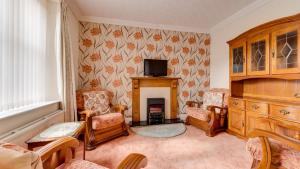 a living room with a tv and chairs and a fireplace at Garrod Avenue in Dunvant