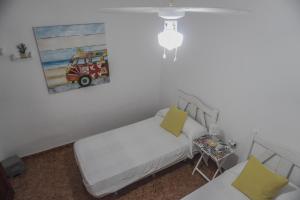Banana Surf House في لوس كريستيانوس: غرفة نوم صغيرة مع سرير ولوحة على الحائط