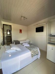 um quarto com uma grande cama branca e uma televisão em Pousada Casa do Luiggi em Penha