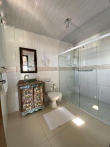uma casa de banho com um WC e uma cabina de duche em vidro. em Pousada Casa do Luiggi em Penha