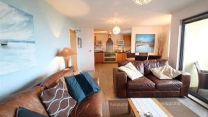sala de estar con 2 sofás de cuero marrón en Fishermans Way, en Swansea