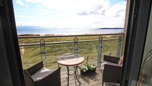 balcón con mesa, sillas y vistas al océano en Fishermans Way, en Swansea