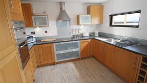 a kitchen with wooden cabinets and stainless steel appliances at Fishermans Way in Swansea