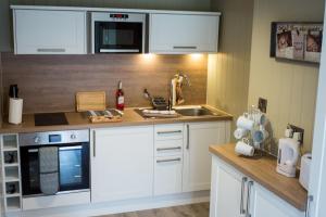 a kitchen with white cabinets and a sink at Sutton Cabins in Stowey