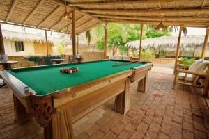 a pool table in a pavilion with a pool at ÓRGANOS BEACH bungalows & suites in Los Órganos