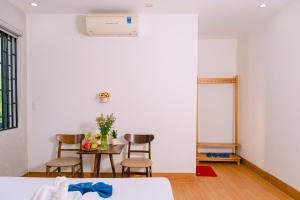 ホイアンにあるVinh Khang Homestayの白い壁の客室で、テーブルと椅子が備わります。