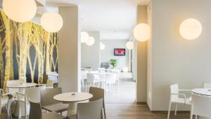 een restaurant met witte tafels en stoelen en bomen aan de muur bij Hotel Eden Garda in Garda
