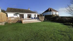 a white house with a porch and a yard at Rhossili Reach in Rhossili