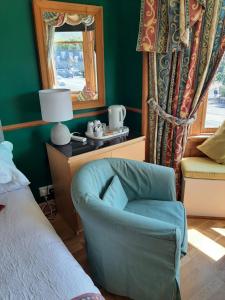a bedroom with a blue chair and a window at Another Room in Edinburgh