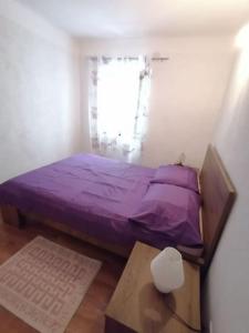 niewielka sypialnia z fioletowym łóżkiem i stołem w obiekcie Apartment in Lovran w mieście Lovran