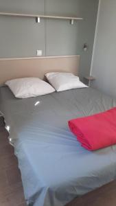 ein großes Bett mit einer roten Decke drauf in der Unterkunft MobilHome de Charlotte - Camping La Falaise 4 étoiles in Narbonne-Plage