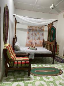 um quarto com uma cama de dossel e uma cadeira em Sanaa Hostel em Zanzibar City