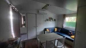 a living room with a table and a blue couch at MobilHome de Charlotte - Camping La Falaise 4 étoiles in Narbonne-Plage