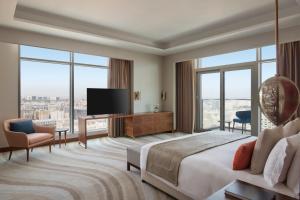 ドーハにあるAbesq Doha Hotel and Residencesのベッドとテレビが備わるホテルルームです。