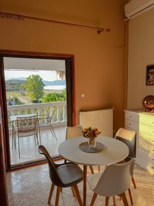 Aktaia Villa في إيريسوس: غرفة طعام مع طاولة وكراسي وشرفة