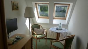 a small room with a table and chairs and a television at Pension Schwark in Bad Doberan