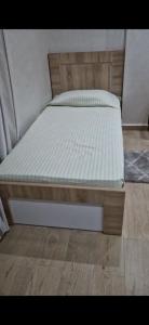 een bed met een wit matras op een houten vloer bij Résidence HALOUA in Oulad Kerroum