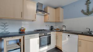 una cocina con electrodomésticos blancos y armarios de madera en William Gammon Dr, en Mumbles