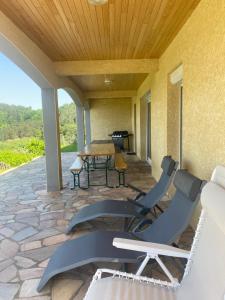 a patio with chairs and a table on a stone patio at Grande maison récente avec vue in Saint-Hilaire