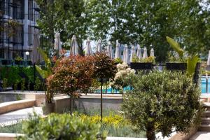 een tuin met parasols, bomen en planten bij Emilia Romana Park in Sunny Beach