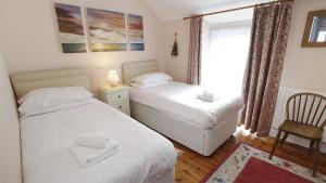 a bedroom with two beds and a chair and a window at Oyster Cottage in The Mumbles