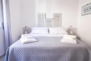 een witte slaapkamer met een bed met 2 kussens erop bij Mencin in Carloforte