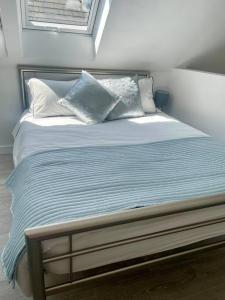 a bed with blue and white pillows on it at Cosy accommodation, easy walk to beach! in Barton on Sea