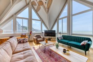 费康Le poséidon, gîte EXCEPTIONNEL face à la mer avec spa, terrasse, 4 chambres UN VRAI COUP DE COEUR的客厅设有绿色沙发和一些窗户。