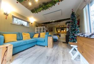 un salon avec un canapé bleu et un arbre de Noël dans l'établissement Sutton Cabins, à Stowey