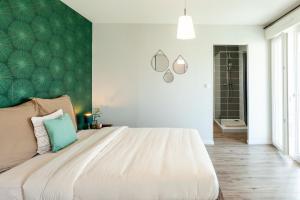 a bedroom with a large bed with a green wall at La Villa Capuccine in Nîmes