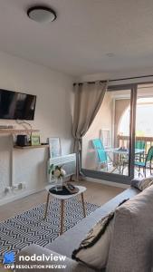 ein Wohnzimmer mit einem Sofa und einem Tisch in der Unterkunft Bastides du Gd Stade - Appart dans la verdure proche plage - Piscine in Saint-Cyprien
