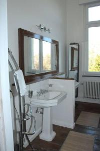 uma casa de banho branca com um lavatório e um espelho em Petit château à la campagne. em Beloeil